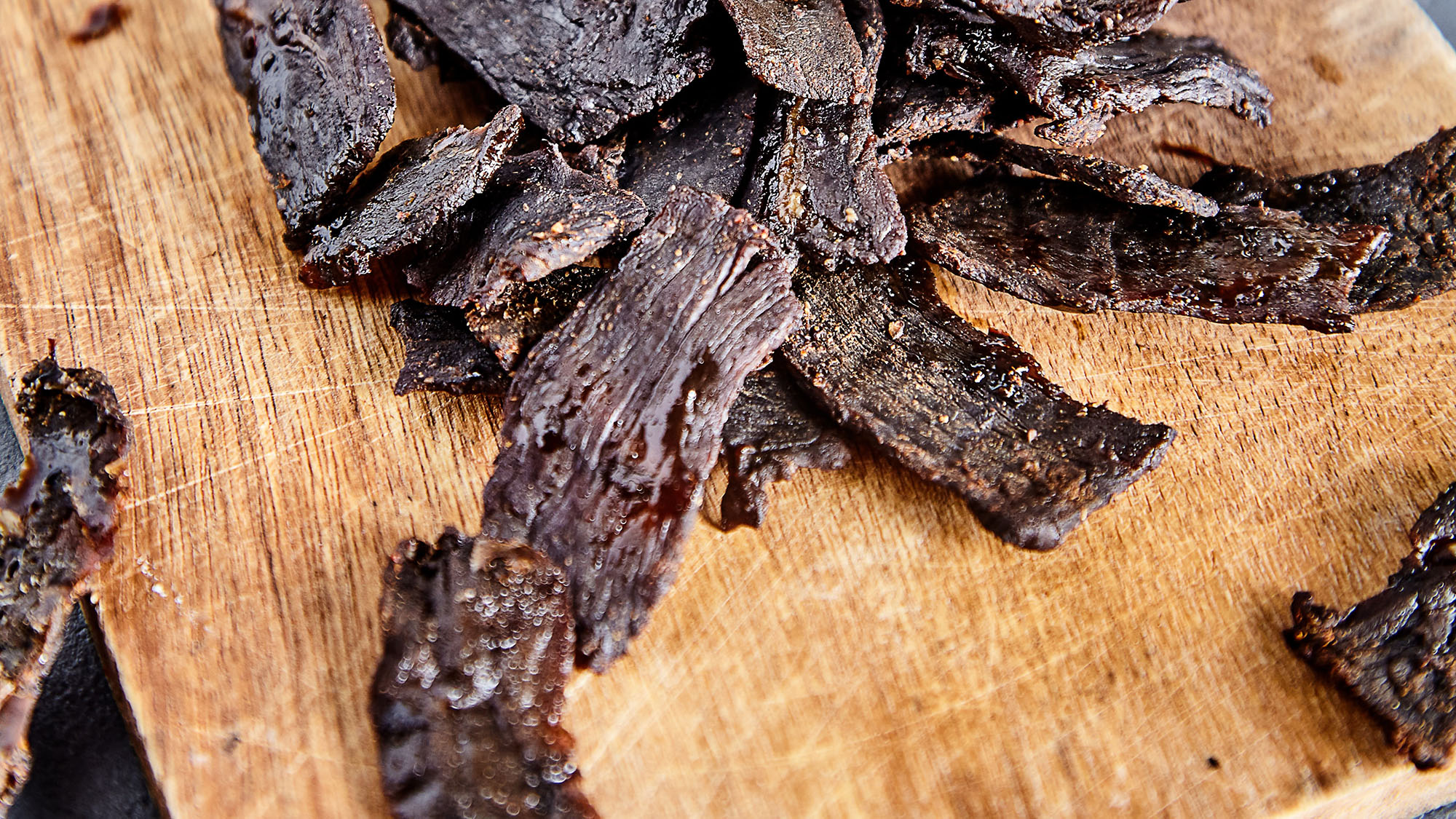 Strips of beef jerky on a wood board. The image was obtained from Unsplash at https://unsplash.com/photos/nlBelQEqwZQ